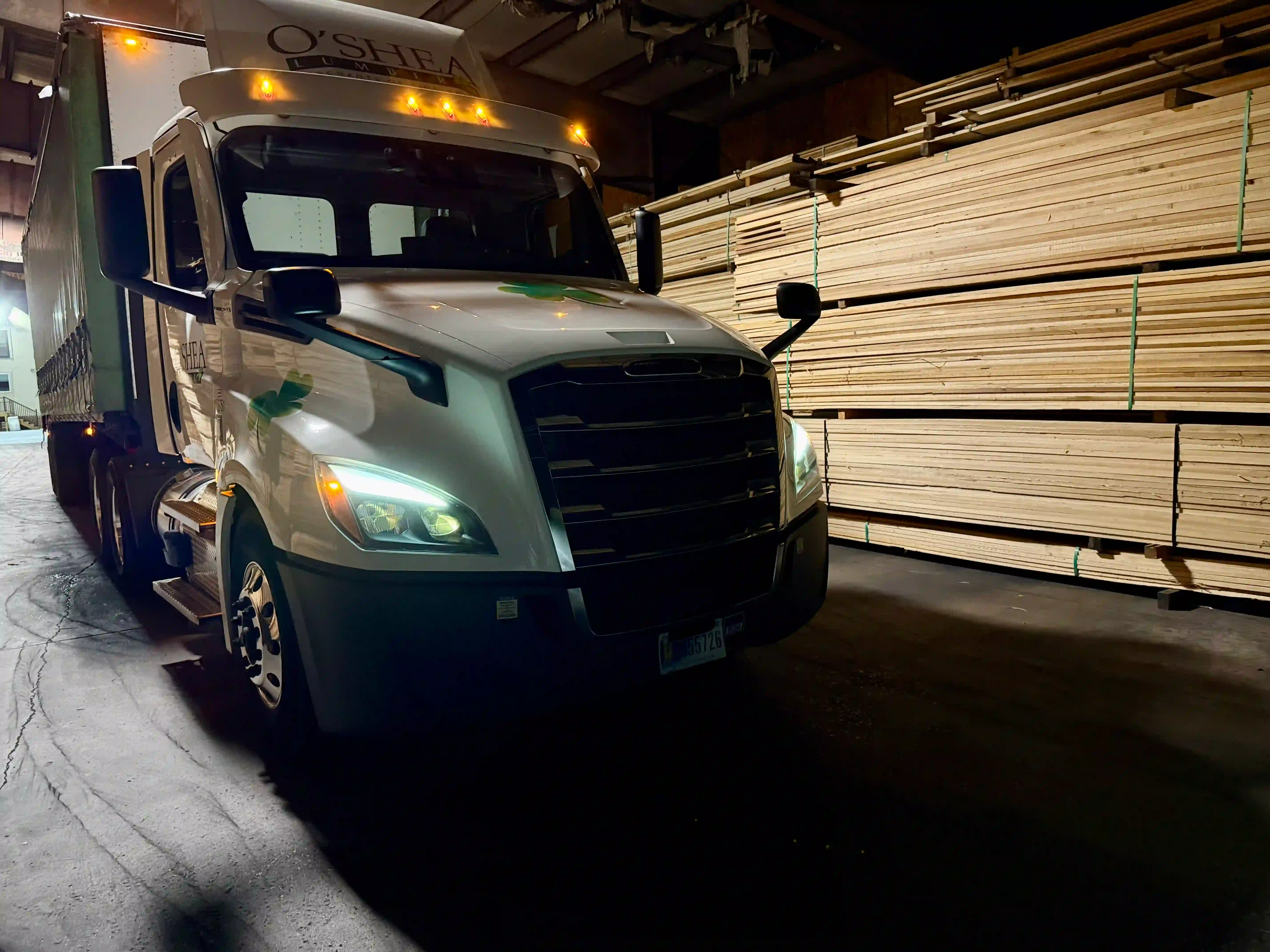 O'Shea Lumber Freightliner at loading dock with lumber stacks